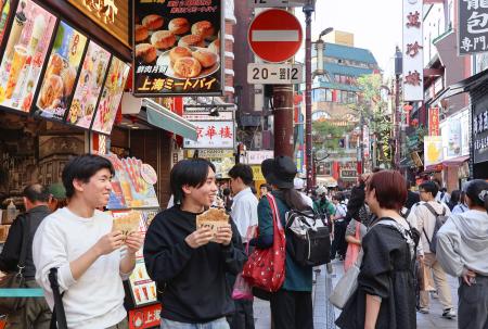横浜中華街の店先でフライドチキンを食べる男性＝１７日、横浜市