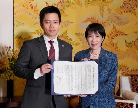 　署名した連立政権合意書を報道陣に示す自民党の高市総裁（右）と日本維新の会の吉村代表＝２０日午後、国会