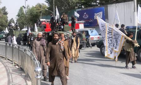 8月、アフガニスタンの首都カブールで、タリバンの旗を掲げて復権4年を誇示する治安部隊員や支持者ら(共同)