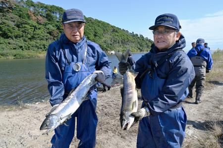 今季初となる漁で取れたサケを持つ木戸川漁協の組合員ら＝２３日午前、福島県楢葉町の木戸川