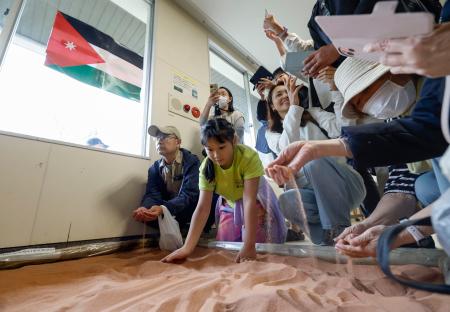 交流イベントで、大阪・関西万博のヨルダン館で展示された砂に触れる人たち＝２５日午前、大阪府吹田市の万博記念公園