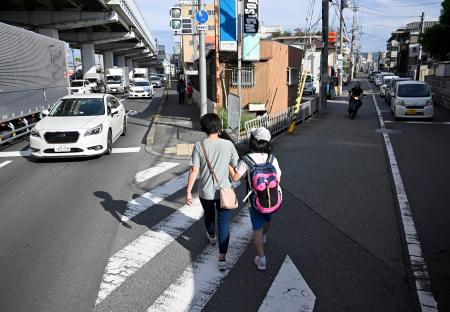 通学に同行し、支援するヘルパー(左)=9月、大阪府豊中市