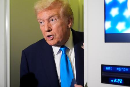 大統領専用機内で記者団の取材に応えるトランプ大統領=25日(AP=共同)