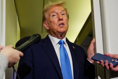 大統領専用機内で記者団の取材に応えるトランプ大統領=25日(ロイター=共同)