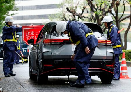 米大使館周辺で、通行車両の検問を実施する警察官=26日午前、東京・赤坂