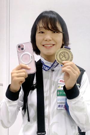 成田空港に帰国し、金メダルと手元に戻ったスマートフォンを手に笑顔を見せるレスリングの藤波朱理=27日