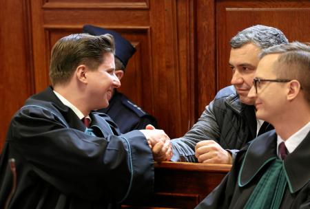 ドイツへの移送を認めない裁判所の判断を受け、弁護士と握手する「ノルドストリーム」破壊事件の容疑者(右奥)=17日、ワルシャワ(ロイター=共同)