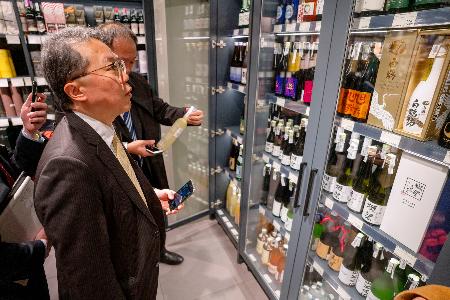 ウクライナ・キーウのスーパーに陳列された日本酒を見る日本の代表団のメンバー=28日(共同)