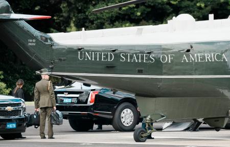 トランプ米大統領を乗せた大統領専用ヘリ、マリーンワンのそばで「核のボタン」とみられるかばんを持ち待機する米軍関係者=29日午前、東京都港区の赤坂プレスセンター