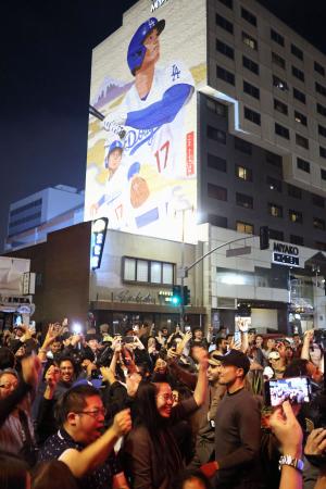 １日、米ロサンゼルス・リトルトーキョーにある大谷翔平選手の壁画の前で、ドジャースのワールドシリーズ連覇を喜ぶファン（共同）