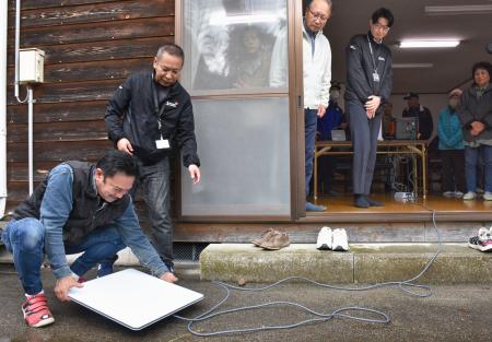 衛星インターネットサービス「スターリンク」を設置する住民ら=2日午前、石川県かほく市