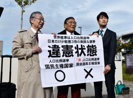 参院選の「1票の格差」訴訟の判決を受け、広島高裁松江支部前で「違憲状態」などと書かれた紙を掲げる原告側の升永英俊弁護士(左)ら=4日午後、松江市