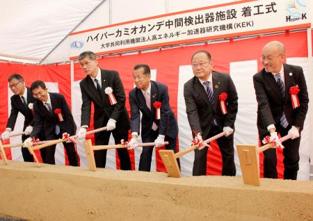 ニュートリノの性質を調べる中間検出器の着工式で、くわ入れする高エネルギー加速器研究機構の浅井祥仁機構長(左から3人目)ら=4日午前、茨城県東海村