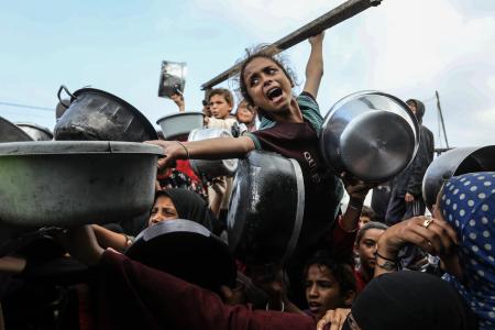 ７日、パレスチナ自治区ガザ南部ハンユニスで、食料配給を受けるために集まる人々（ゲッティ＝共同）