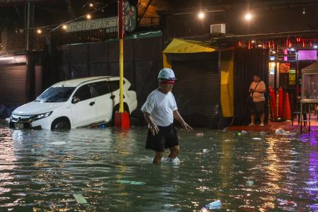 台風が直撃し浸水した道路を歩く男性＝９日、マニラ首都圏（ゲッティ＝共同）