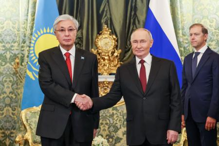 １２日、モスクワで会談前に握手するロシアのプーチン大統領とカザフスタンのトカエフ大統領（左）（ロシア大統領府提供・タス＝共同）