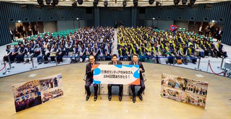 大阪・関西万博の運営を支えたボランティアスタッフと写真に納まる万博協会の石毛博行事務総長（壇上左）ら＝１５日午後、大阪市北区
