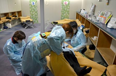 神戸港で行われた「病院船」の活用に向けた訓練で、患者の治療手順を確認する医療関係者ら＝１６日午後