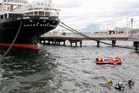 女性とみられる上半身だけの遺体が発見された「氷川丸」付近の海中を捜索する神奈川県警のダイバーら＝１８日午前、横浜市