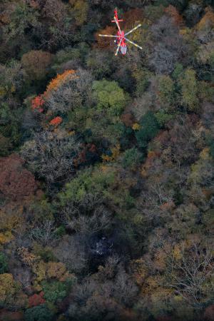 小型機が墜落したとみられる現場(下)で救助活動を行う消防ヘリ=18日午後1時5分、福岡県八女市(共同通信社ヘリから)