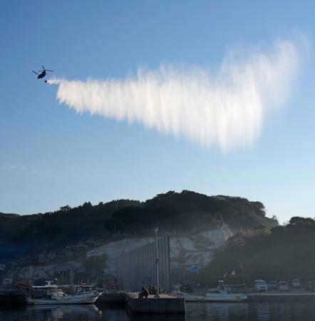 大分市佐賀関の大規模火災現場付近で上空から放水する自衛隊のヘリコプター＝２０日午前８時４分