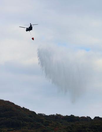 大分市佐賀関の大規模火災現場付近で上空から散水する自衛隊のヘリコプター＝２０日午前１０時２６分