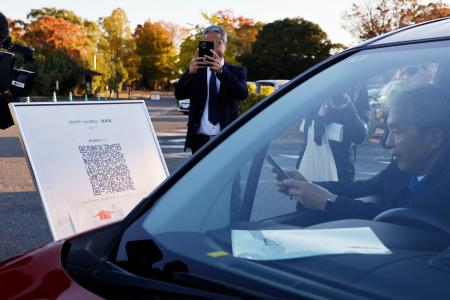 車中泊避難の実証実験で、スマートフォンを使って受け付けをする参加者＝２２日午後、熊本市