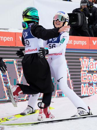 Ｗ杯ジャンプ女子個人第１戦で２回目の飛躍を終え、伊藤有希と抱き合う丸山希（右）。Ｗ杯初優勝を決めた＝リレハンメル（共同）