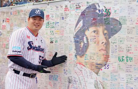 ファン感謝イベントに参加し、応援ボードの前でポーズをとるヤクルト・村上=23日、神宮