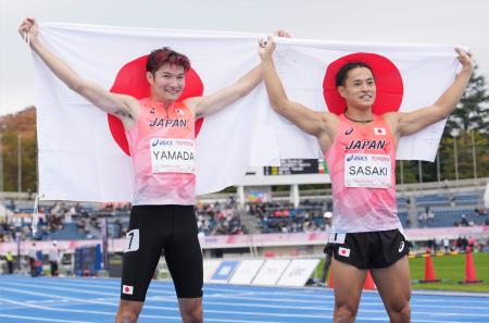 　男子２００メートルで２位となり、日の丸を掲げる山田真樹（左）と７位の佐々木琢磨＝駒沢陸上競技場