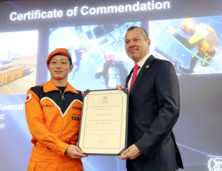 式典で表彰状を受け取る、海上保安庁特殊救難隊の野田健斗隊長（左）＝２４日、ロンドンの国際海事機関本部（共同）