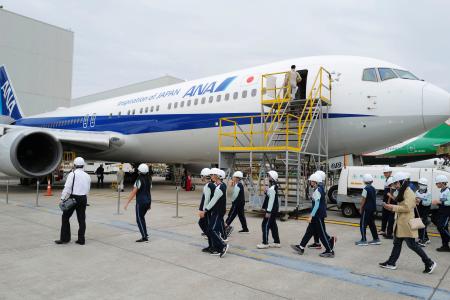 整備中の航空機を見学する小学生ら＝２５日、台湾・桃園市（共同）