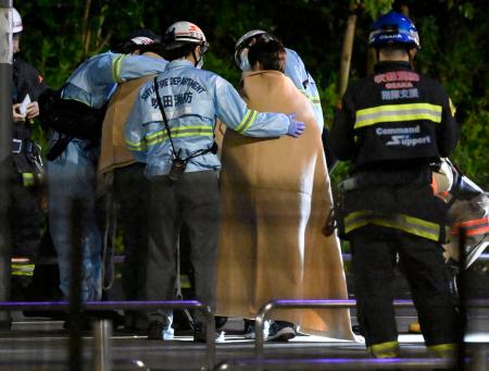閉じ込められた観覧車から救助され、消防隊員に毛布をかけられる乗客=26日午前2時42分、大阪府吹田市