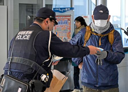 ＪＲ天竜川駅で利用者に事件の概要が書かれたチラシ入りティッシュを手渡す警察官＝２７日午前、浜松市