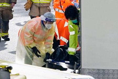 火災現場から運び出される遺体を覆ったとみられる黒い袋＝２８日、香港北部・新界地区大埔（共同）