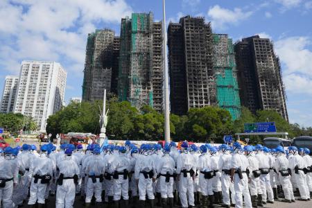大規模火災が起きた香港北部の高層住宅群近くに集まった防護服姿の捜索隊員ら＝２９日（共同）