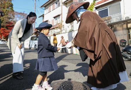 天台宗の「全国一斉托鉢」で僧侶（右）に浄財を渡す親子＝１日午前、大津市
