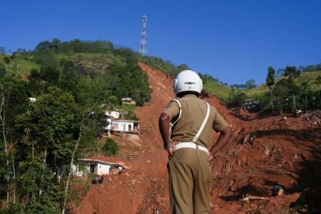 ２日、スリランカ中部キャンディで、豪雨による土砂崩れの現場を見る警察官（ロイター＝共同）
