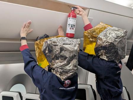 日航の訓練施設で、荷物棚に消火器を向ける客室乗務員＝２日午後、東京都内