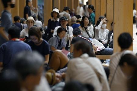 大阪メトロ中央線が運転見合わせとなり、大屋根リングの下で休憩する人たち＝８月１４日午前１時８分、大阪市此花区の夢洲