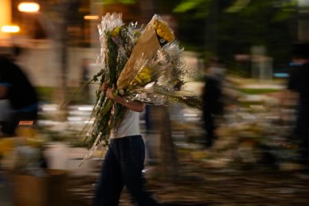 高層住宅群の大規模火災現場近くの公園から撤去される花束＝７日、香港（共同）
