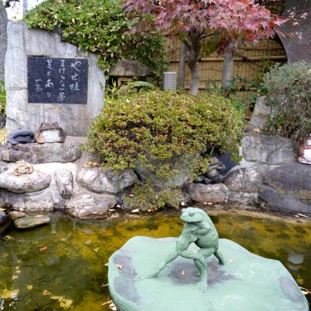 　〈やせ蛙まけるな一茶是にあり〉の句碑と、カエルが相撲を取るオブジェ＝東京都足立区