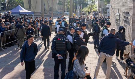 リンゴ日報の創業者、黎智英氏への判決公判が開かれる裁判所前を警戒する治安当局者ら=15日、香港(共同)