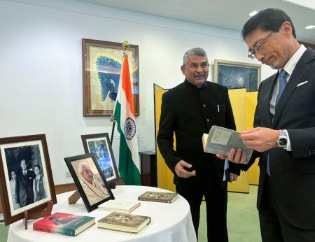 故アシャさんの関連書籍を見る小野啓一駐インド大使。左はアシャさんの次男サンジェイさん＝１７日、ニューデリー（共同）