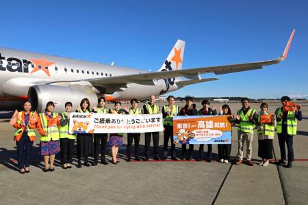 駐機場で記念写真に納まるジェットスター・ジャパンの関係者ら=18日午前、成田空港