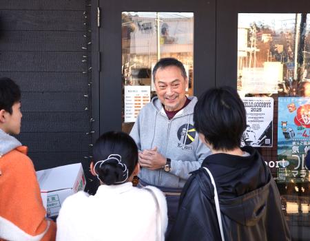 カフェ「K―port」の店頭で客を出迎える俳優渡辺謙さん=20日午前、宮城県気仙沼市