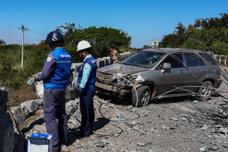 ２０日、カンボジア北西部でタイ軍の戦闘機による空爆を受けた橋を調べる政府職員ら（ゲッティ＝共同）