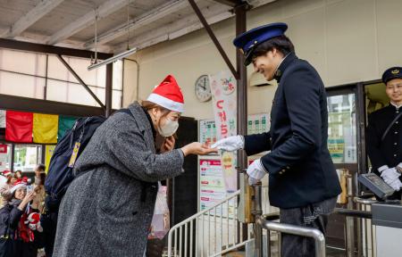 　水間鉄道開業１００周年の記念切符を受け取る乗客（左）＝２４日午前、大阪府貝塚市の貝塚駅