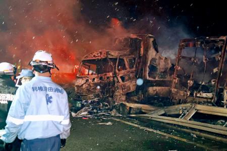関越自動車道の事故現場で焼けた車と、活動する消防関係者ら＝２７日午前３時３分、群馬県みなかみ町
