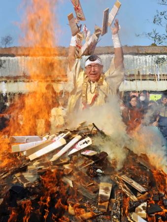 成田山新勝寺の「納め札お焚き上げ」で、火柱にお札を投げ入れる山伏姿の僧侶＝２８日午前、千葉県成田市